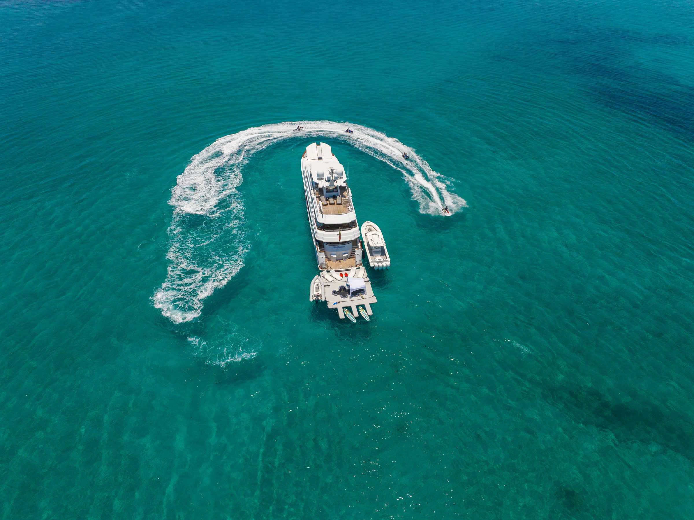 Aerial view of jet skis circling a superyacht in the Bahamas